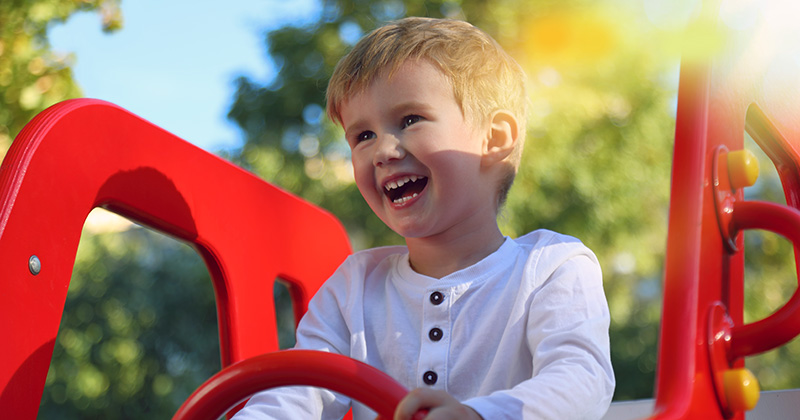 Happy toddler boy holding toy steering wheel