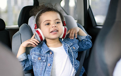 Girl in car back seat with headphones up