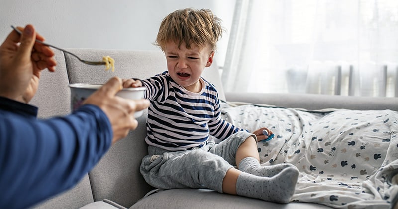 Unhappy toddler boy refusing breakfast